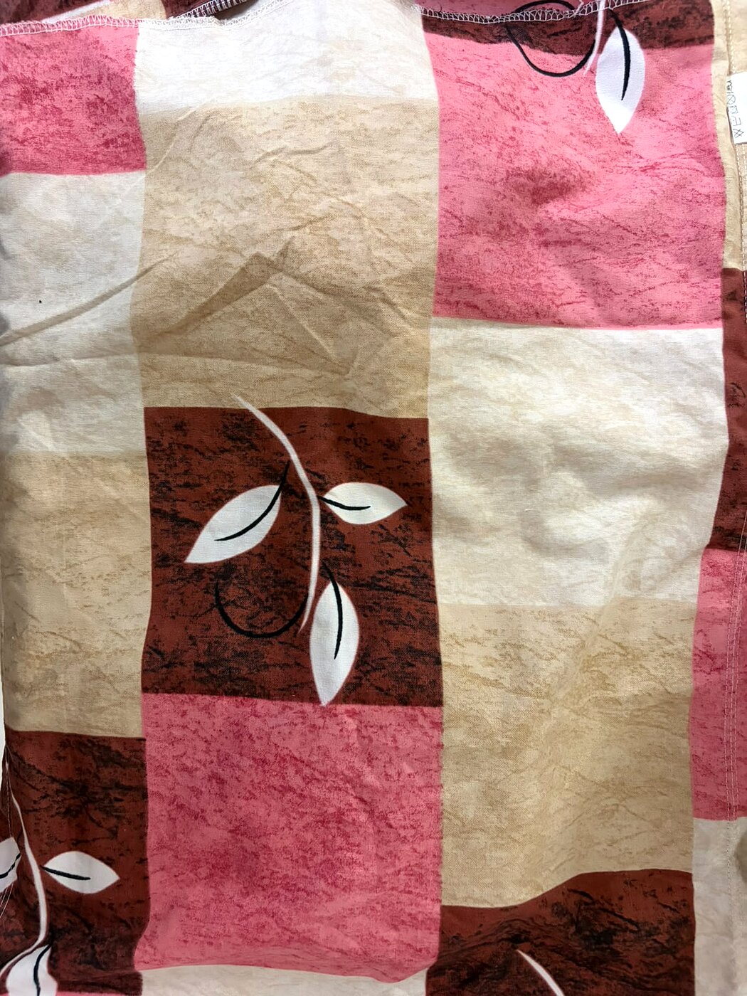 Close-up of budget bedsheet flat printed leaf pattern with no embroidery or texture