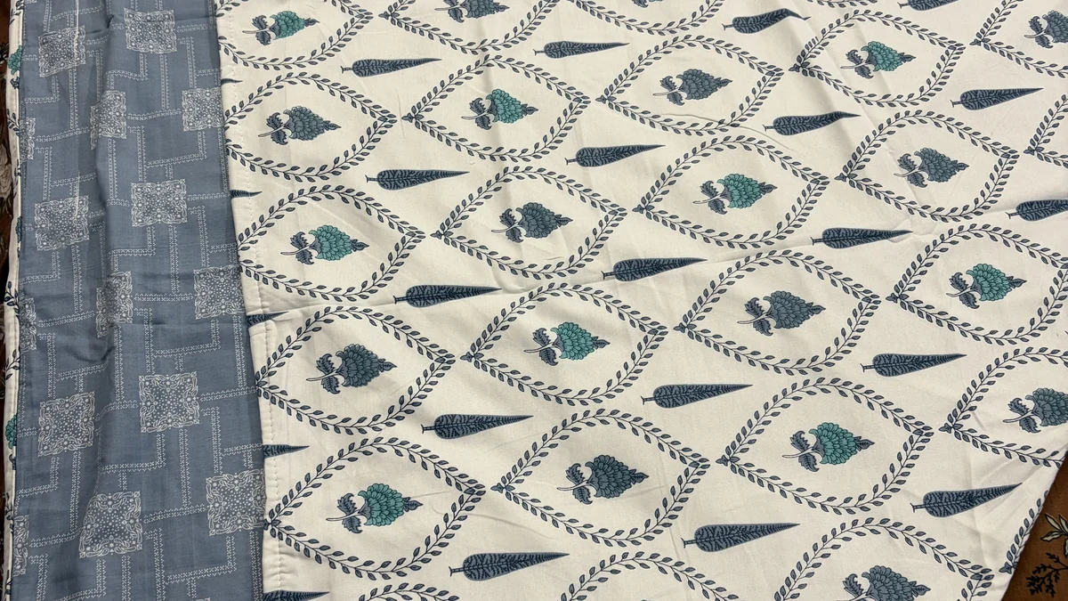 Reversible cotton dohar showing both sides — ivory Mughal print and steel-blue bandhani — with the blue border